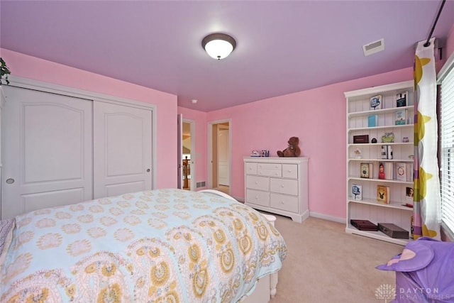 bedroom with light colored carpet, visible vents, a closet, and baseboards