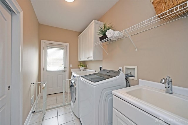 washroom featuring washer and dryer, cabinet space, light tile patterned flooring, and a sink