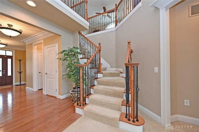 foyer entrance with baseboards, wood finished floors, stairs, and crown molding