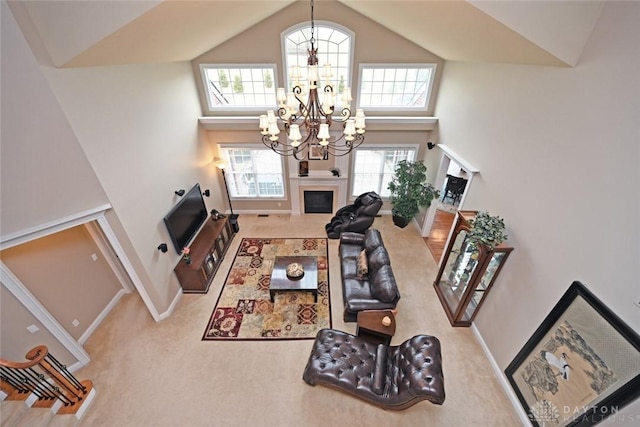 carpeted living area featuring high vaulted ceiling, a fireplace, baseboards, and a chandelier