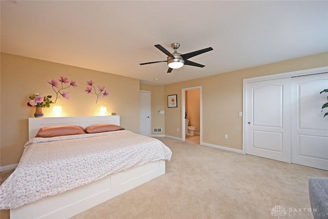 bedroom featuring visible vents, baseboards, light colored carpet, a closet, and ensuite bath