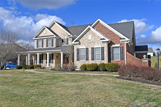 view of front facade featuring a front yard, covered porch, and stone siding