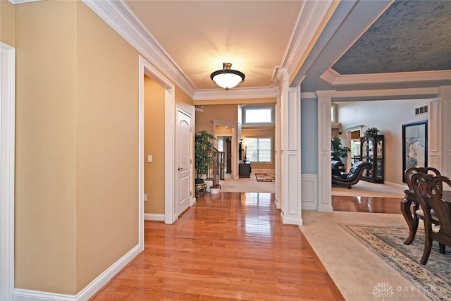 entrance foyer with light wood-type flooring, visible vents, crown molding, decorative columns, and baseboards