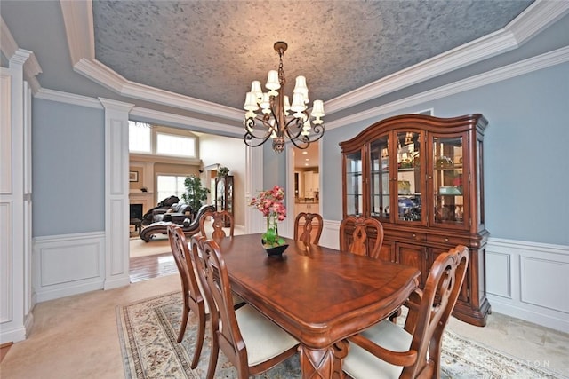 dining area featuring a chandelier, a decorative wall, a raised ceiling, and decorative columns