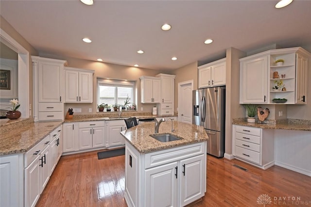 kitchen featuring white cabinetry, stainless steel fridge, light wood finished floors, and a sink