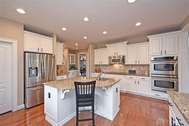 kitchen with white cabinets, light wood-style flooring, tasteful backsplash, and appliances with stainless steel finishes