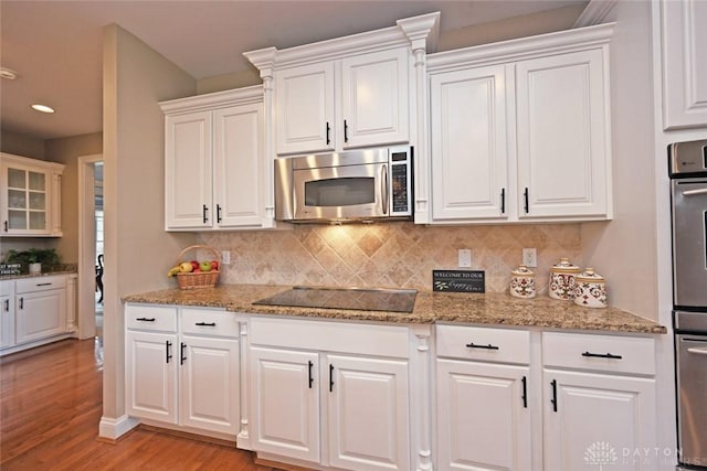 kitchen featuring decorative backsplash, white cabinets, stainless steel appliances, and light wood-style flooring