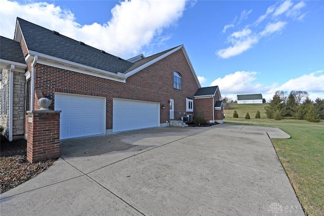 view of side of property with a yard, brick siding, roof with shingles, and concrete driveway