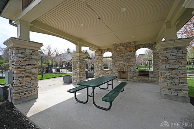 view of patio / terrace featuring an outdoor stone fireplace and fence