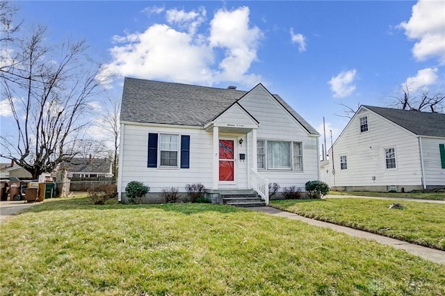 bungalow-style home featuring entry steps, a shingled roof, and a front lawn