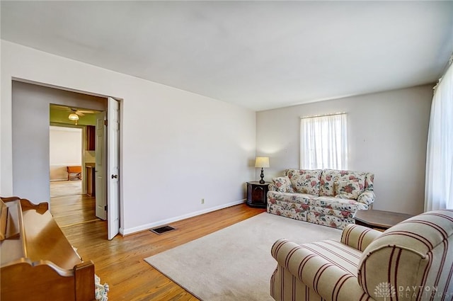 living room with wood finished floors, visible vents, and baseboards