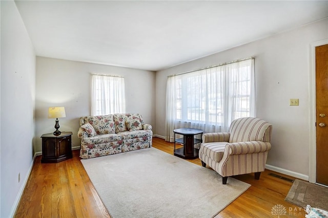 living area with wood finished floors, visible vents, and baseboards