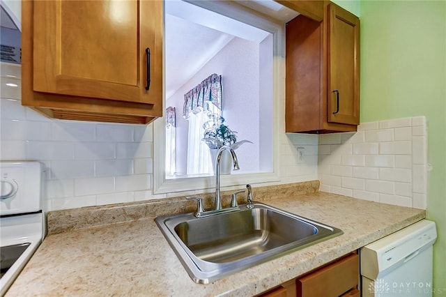 kitchen featuring brown cabinetry, a sink, decorative backsplash, light countertops, and dishwasher