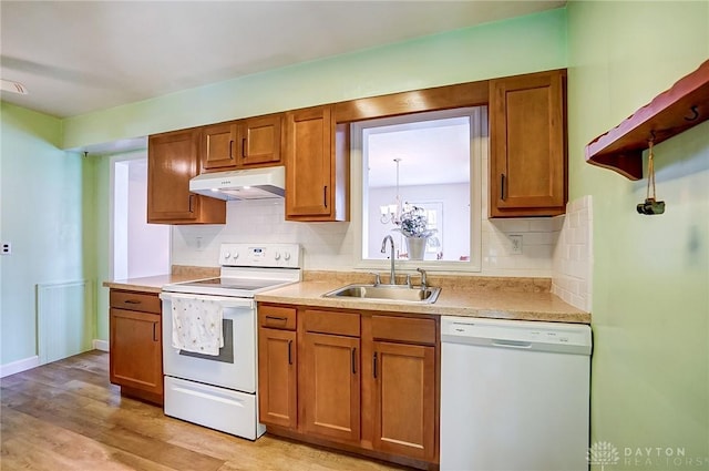 kitchen featuring under cabinet range hood, a sink, white appliances, brown cabinetry, and light countertops