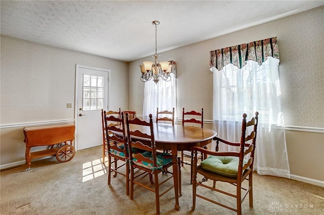 carpeted dining room with a notable chandelier and a textured ceiling