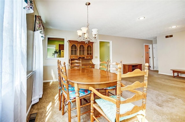 carpeted dining room featuring a notable chandelier, baseboards, and visible vents