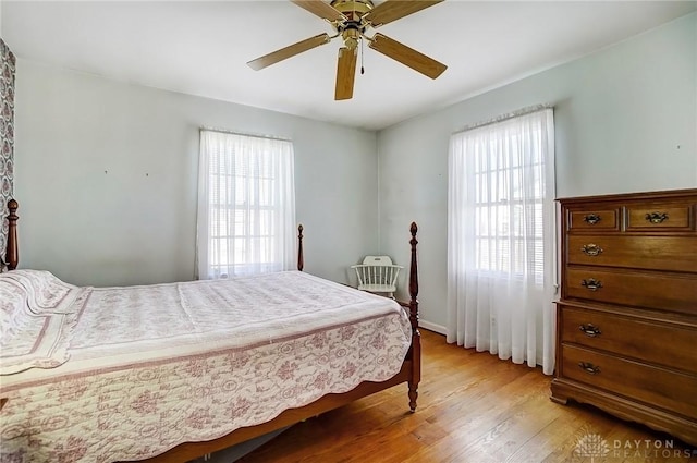 bedroom with multiple windows, light wood-style floors, and ceiling fan