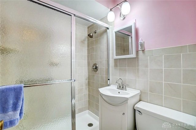 full bathroom with toilet, tile walls, a stall shower, and vanity