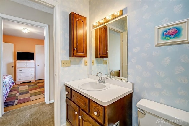 bathroom with wallpapered walls, toilet, and vanity