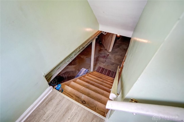 staircase featuring baseboards and wood finished floors