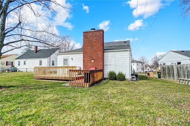 rear view of property with a yard, a deck, a chimney, and fence