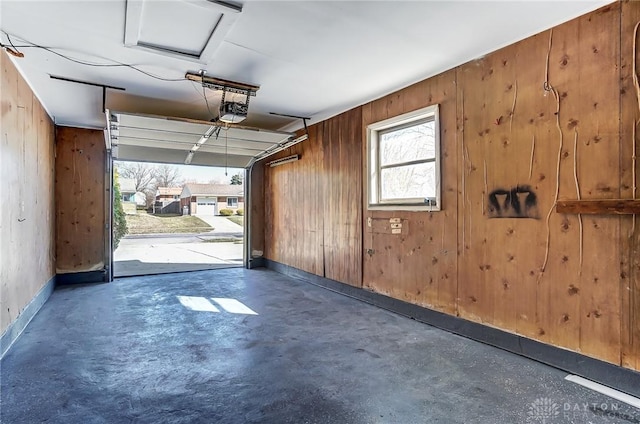 garage with wooden walls, a garage door opener, and baseboards