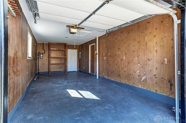 garage with a garage door opener, baseboards, and wood walls