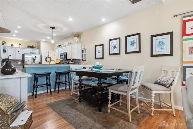 dining area with baseboards, recessed lighting, a textured ceiling, and light wood-style floors