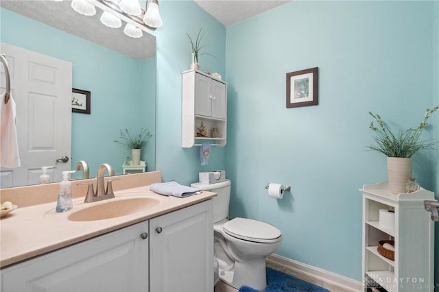 bathroom featuring a textured ceiling, toilet, vanity, and baseboards