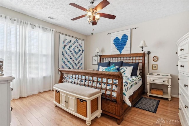 bedroom featuring visible vents, light wood-style flooring, and a textured ceiling