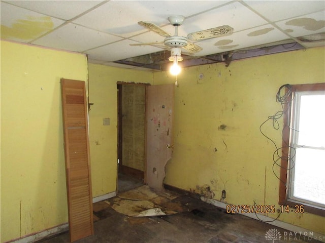 empty room with a paneled ceiling, plenty of natural light, and a ceiling fan