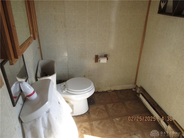 bathroom featuring toilet and tile walls