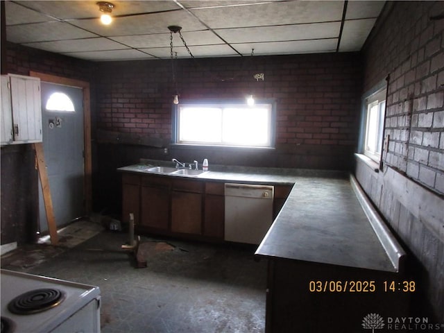 kitchen with brick wall, a drop ceiling, white appliances, white cabinetry, and a sink