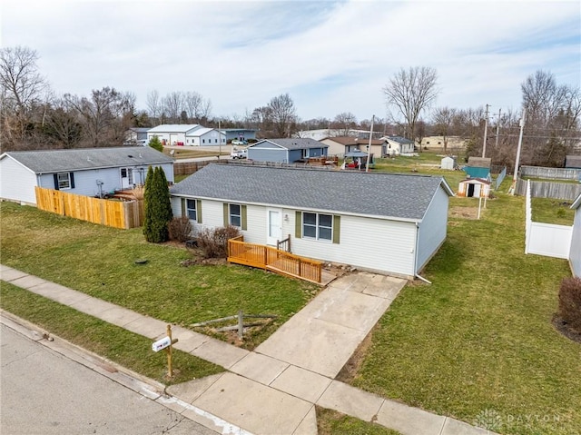 ranch-style home with a front yard, fence, a residential view, and a shingled roof