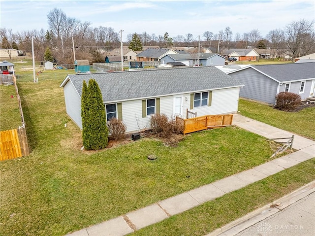 ranch-style home with a residential view, a front lawn, roof with shingles, and fence