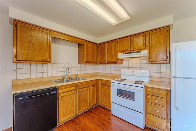 kitchen with under cabinet range hood, white appliances, light countertops, and a sink