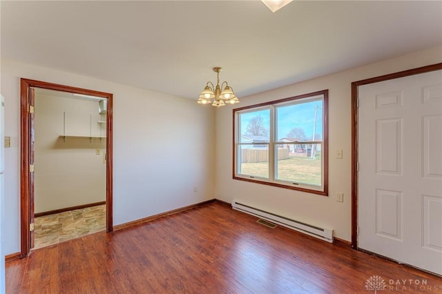 unfurnished room with baseboards, a baseboard heating unit, an inviting chandelier, and dark wood-style flooring