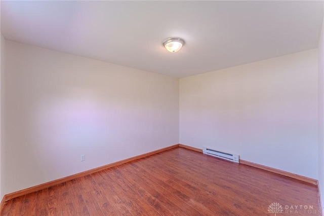 empty room with a baseboard radiator, baseboards, and wood finished floors