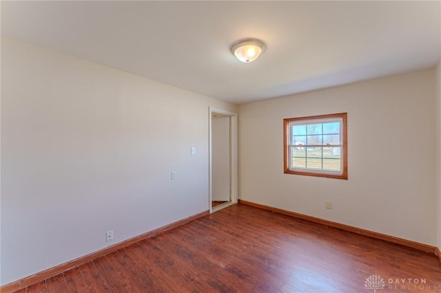 spare room featuring baseboards and wood finished floors