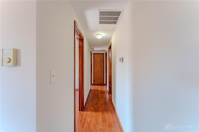 hallway featuring light wood-type flooring, visible vents, and baseboards