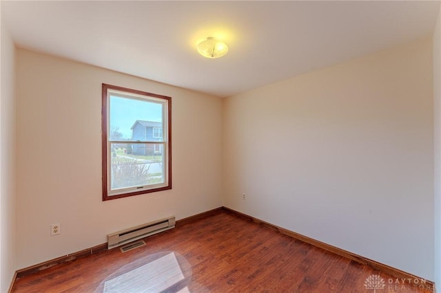 empty room featuring a baseboard radiator, baseboards, and wood finished floors