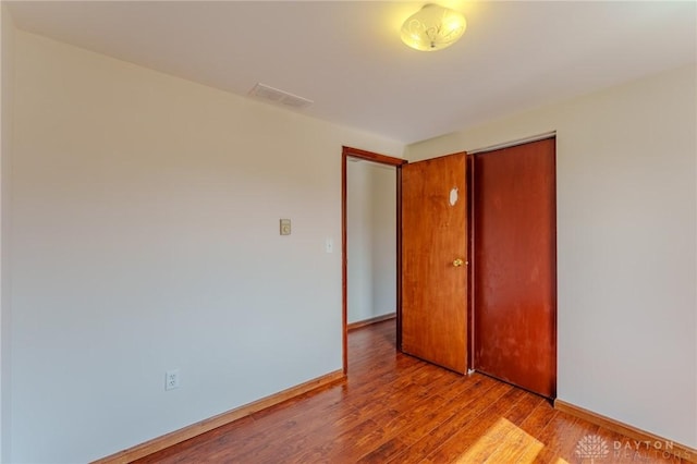 spare room with visible vents, baseboards, and wood finished floors