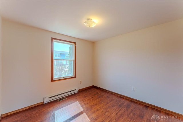 empty room with baseboard heating, visible vents, baseboards, and wood finished floors