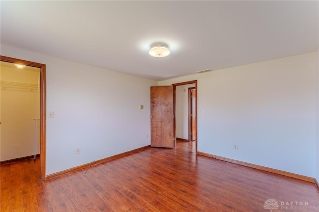 unfurnished room with wood finished floors, visible vents, and baseboards