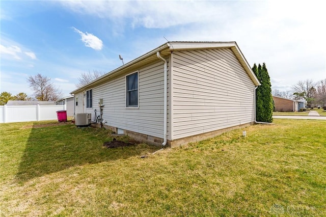 view of side of home with central air condition unit, a yard, and fence