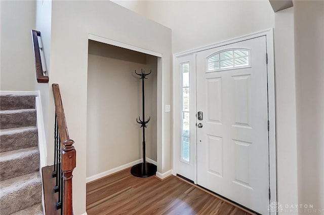 foyer entrance with stairway, baseboards, a healthy amount of sunlight, and wood finished floors