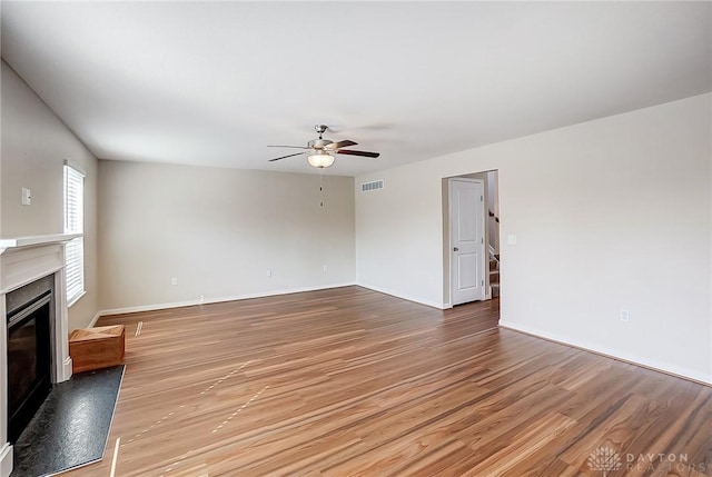 unfurnished living room featuring visible vents, baseboards, ceiling fan, light wood-style floors, and a glass covered fireplace