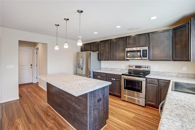 kitchen featuring stainless steel appliances, light wood-style floors, dark brown cabinets, and a center island