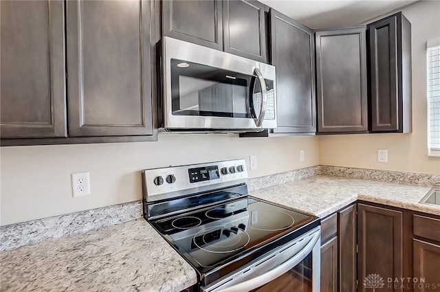 kitchen featuring stainless steel appliances, dark brown cabinets, and light countertops