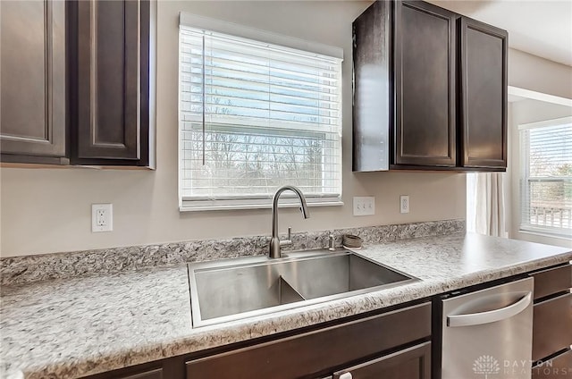 kitchen featuring stainless steel dishwasher, light countertops, dark brown cabinets, and a sink